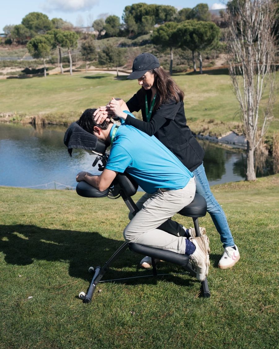 Penélope dando un masaje en silla a un golfista junto al lago del campo